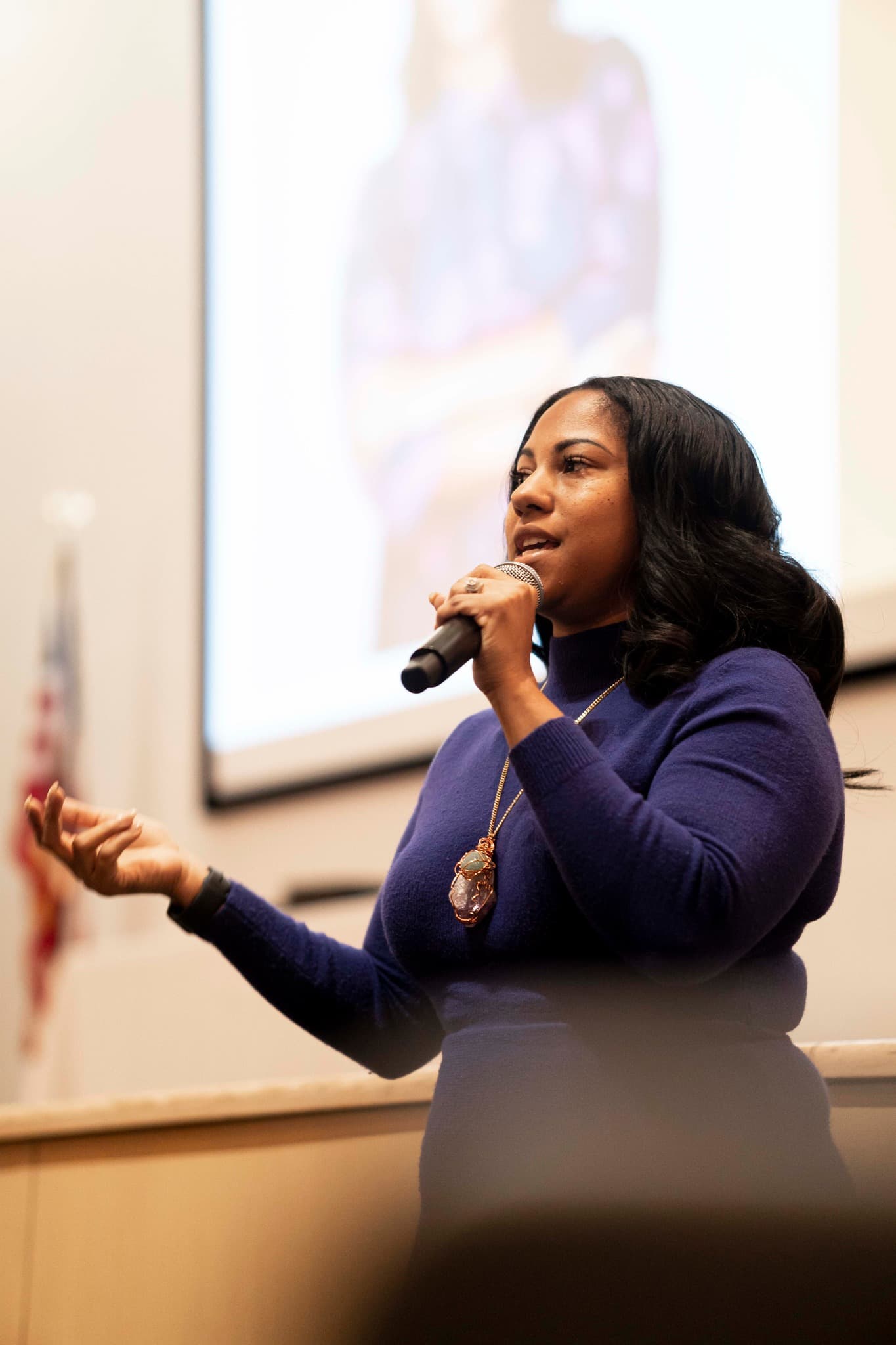 Black woman on stage with a microphone speaking