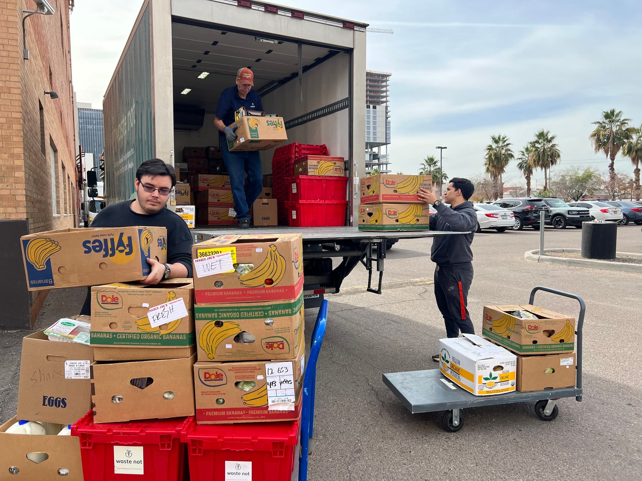 3 men moving boxes of food off a truck onto carts